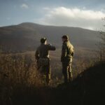 2 men standing on brown grass field during daytime